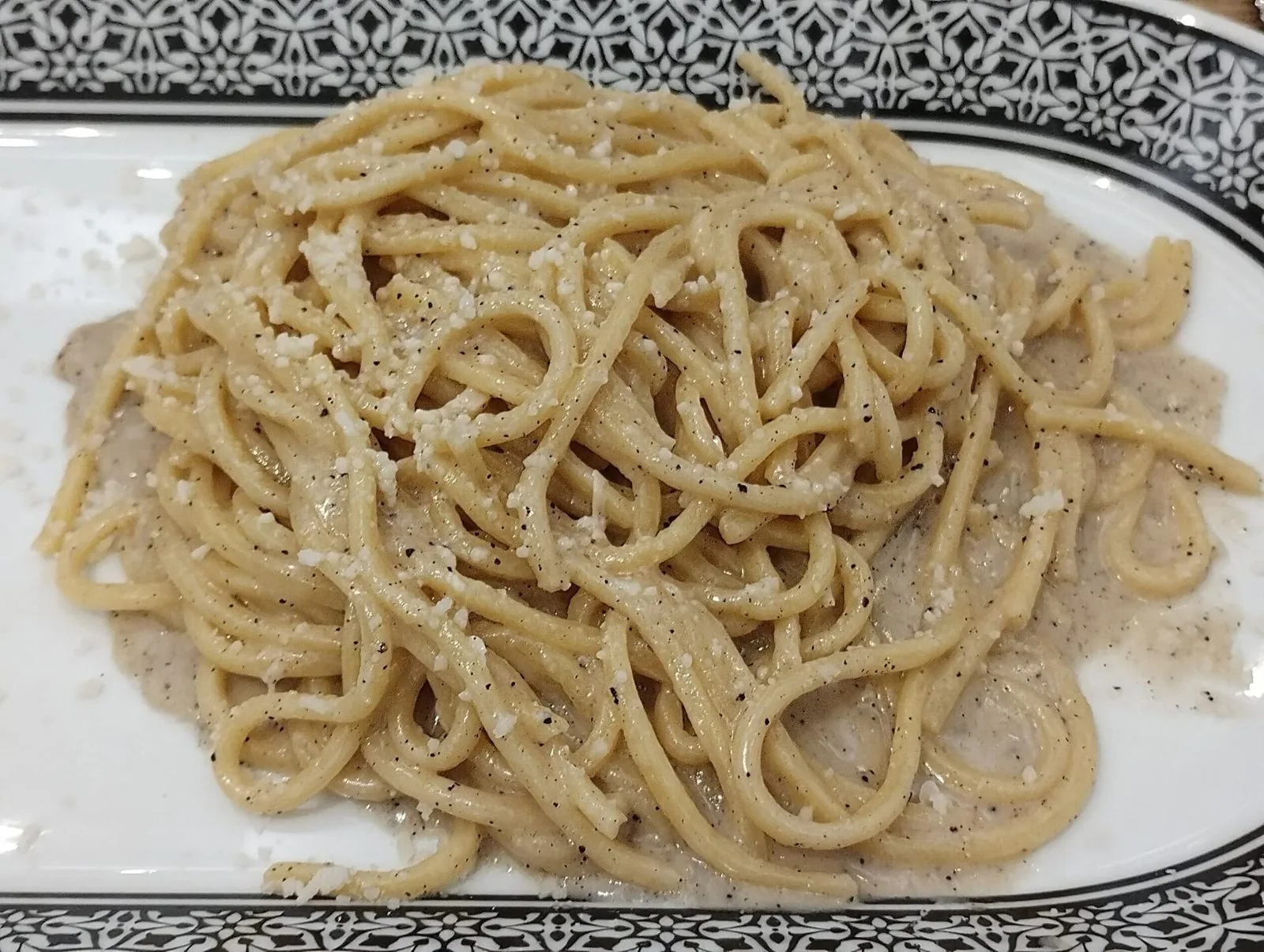 Piatto di spaghetti cacio e pepe con pecorino e pepe nero